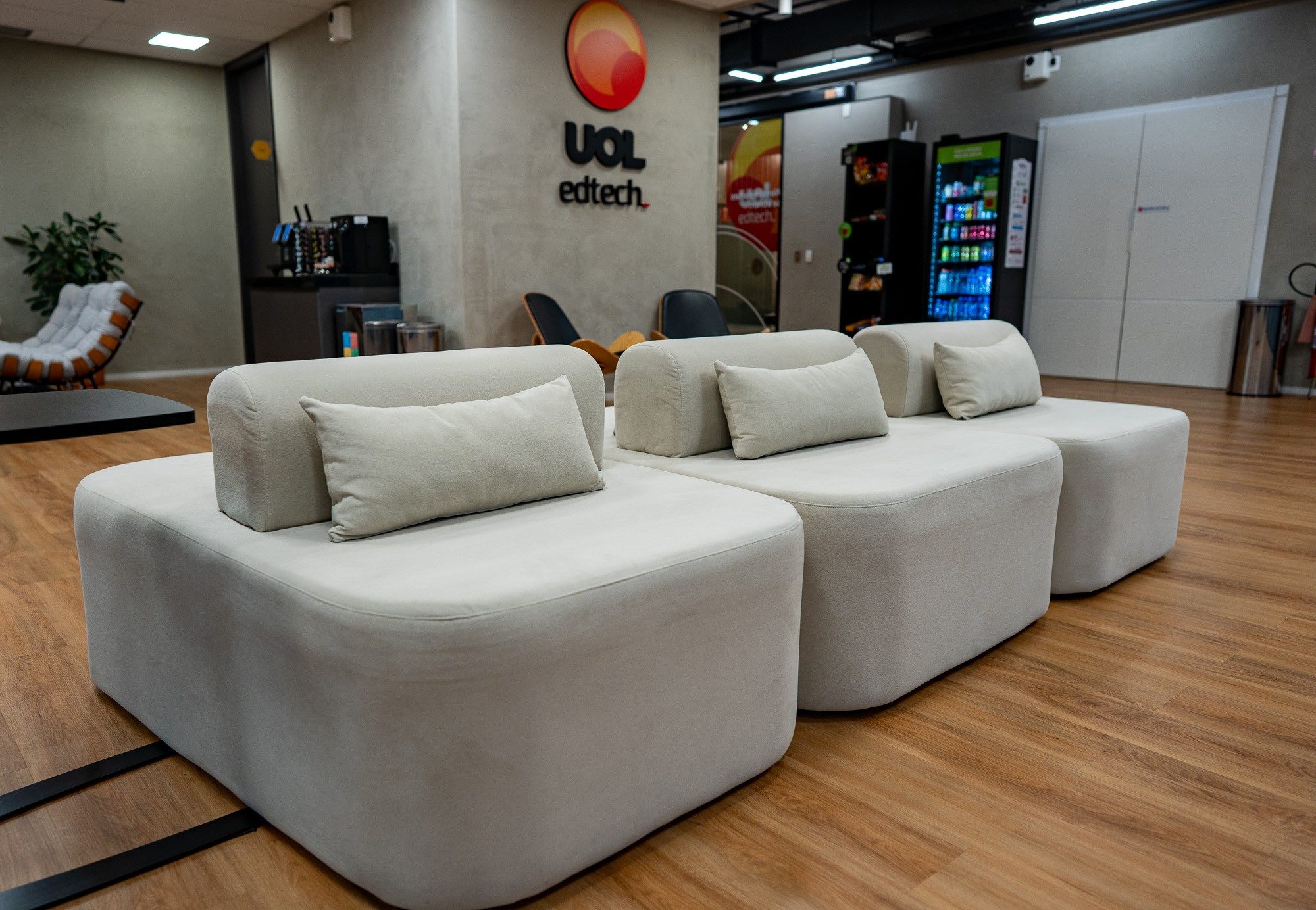 Lounge da UOL EdTech, com poltronas modulares e identidade visual na parede
